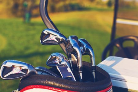Golf clubs drivers over green field background